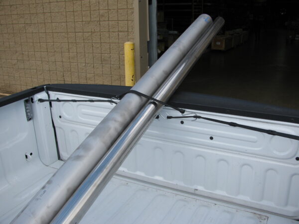 adjustable strap around a long metal pipe in the back of a pick up truck