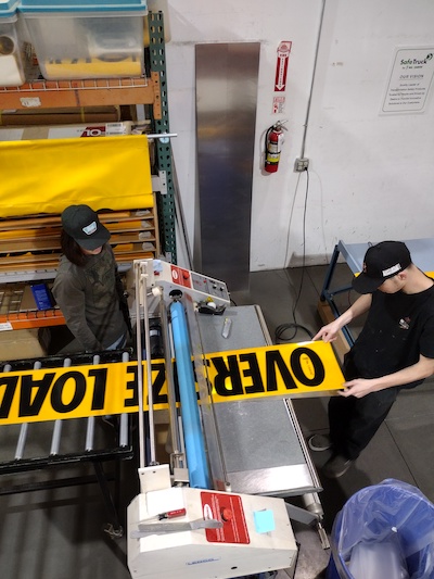 Employees making an Aluminum Reflective OVERSIZE LOAD sign