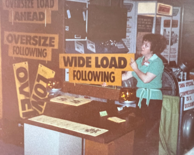 Ms. Carita at a Truck Show with her WIDE LOAD signs in the 1970’s.