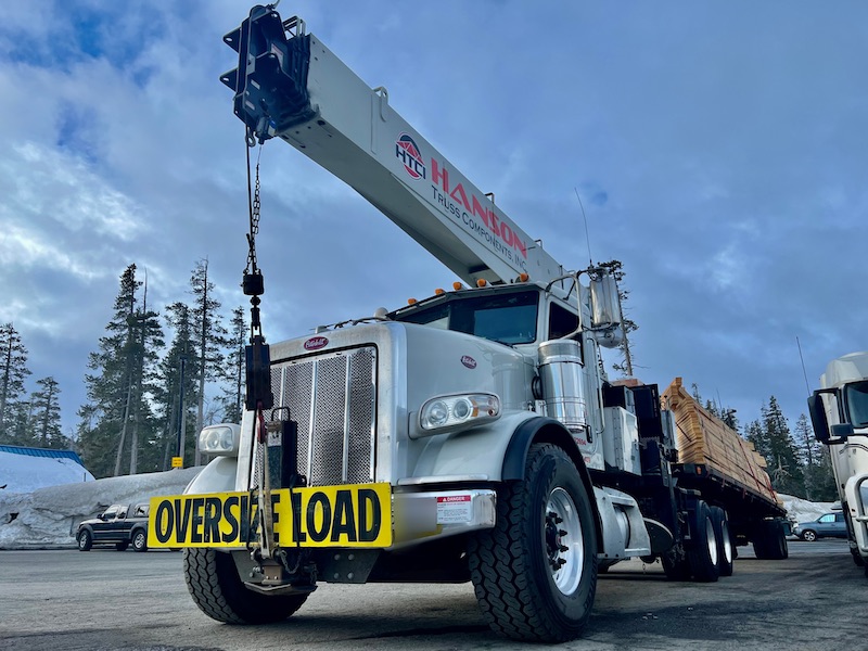 OVERSIZE LOAD truck and trailer with a yellow OVERSIZE LOAD safety sign