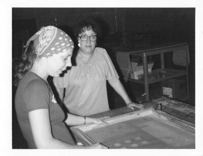 Ms. Carita working in the shop with a screen and an employee on truck safety