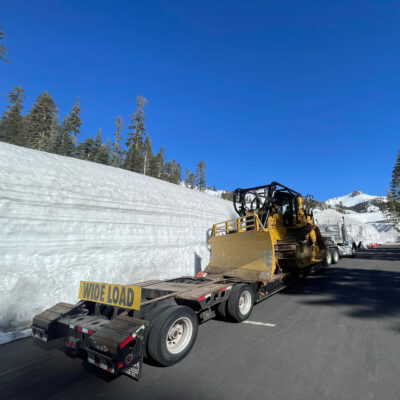 National Park Service Tractor Trailer with a WIDE LOAD Sign in a parking lot surrounded by walls of snow