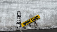 Snowboard and Wide Load Sign against snowbank