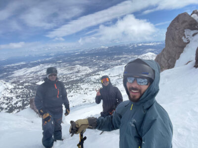 Ben, Philip, and Josh on Lassen Peak above a snow and forest covered area