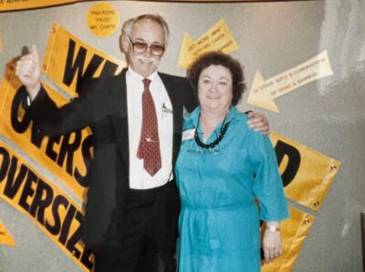 Merritt and Carita Mosby standing in front of Wide Load and Oversize Load Banners at a tradeshow