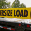 oversize load bungee banner mounted on a flatbed trailer with the stake pocket banner brackets