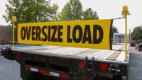oversize load bungee banner mounted on a flatbed trailer with the stake pocket banner brackets