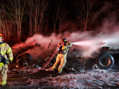 firefighter holding a hose and extinguishing the last part of the truck fire